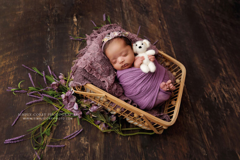 newborn photographer near Atlanta, baby girl in basket with purple wrap and flowers