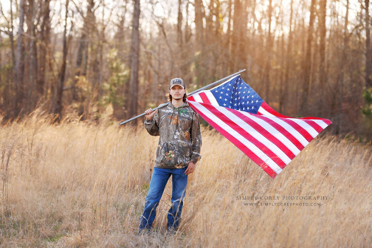 Douglasville senior portrait photographer, teen with American flag outside in field