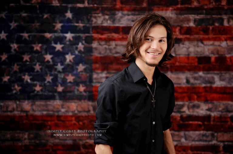 senior portrait photographer near Atlanta, teen boy in studio with American flag backdrop