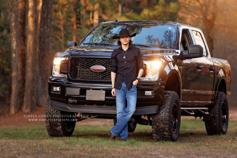 senior portrait photographer near Hiram, teen boy in cowboy hat outside with Ford truck