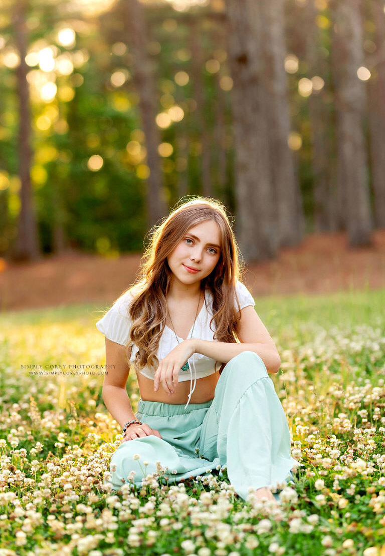 senior portrait photographer near Atlanta, teen girl outside in grass and clover in spring