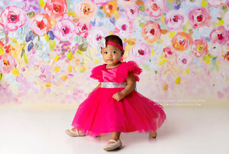 baby photographer near Bremen, girl in pink dress on colorful floral backdrop