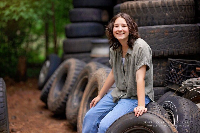 senior portrait photographer near Atlanta, teen girl outside with tires