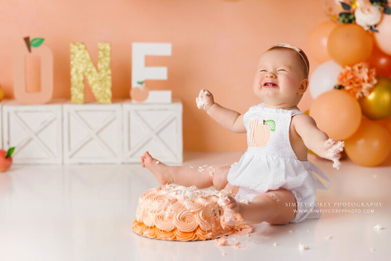 Dallas Georgia cake smash photographer, baby girl laughing with foot in peach cake