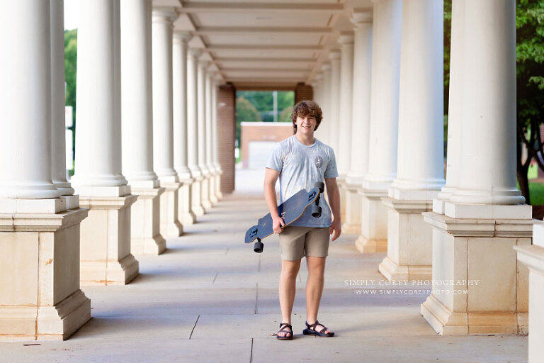 Newnan senior portrait photographer, teen standing with skateboard between columns