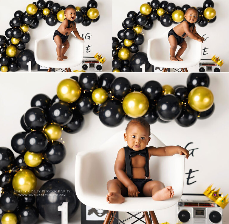 baby photographer near Newnan, boy in chair for studio milestone session with black gold balloon garland