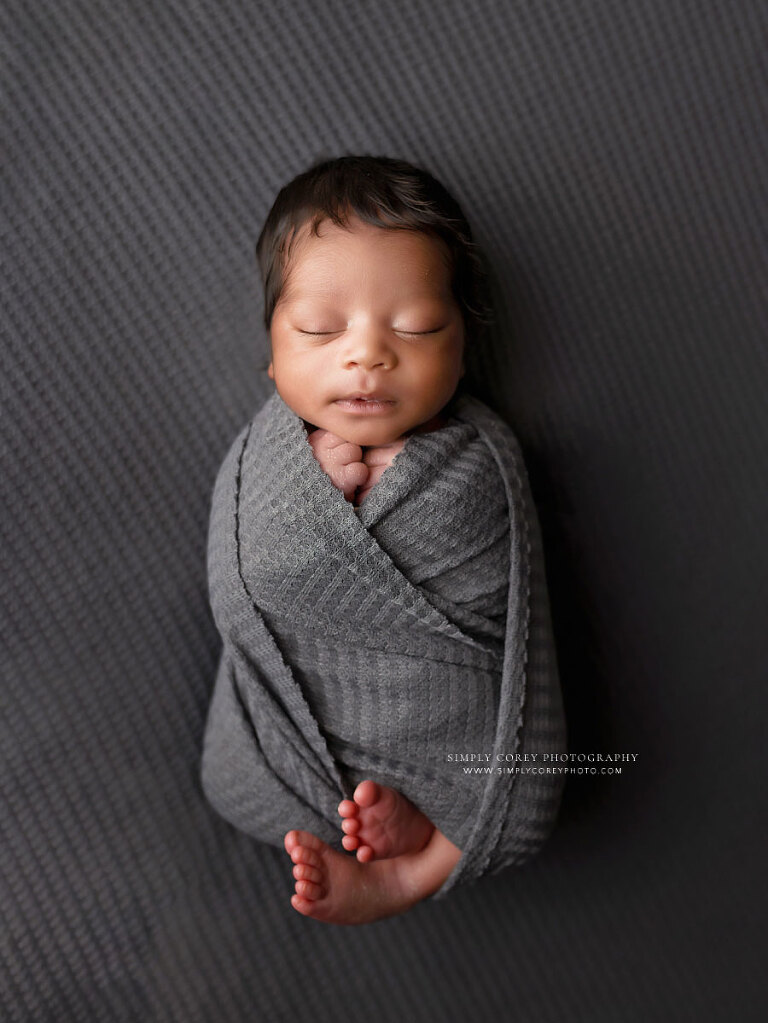 newborn photographer near Tyrone, baby boy in gray swaddle during studio session