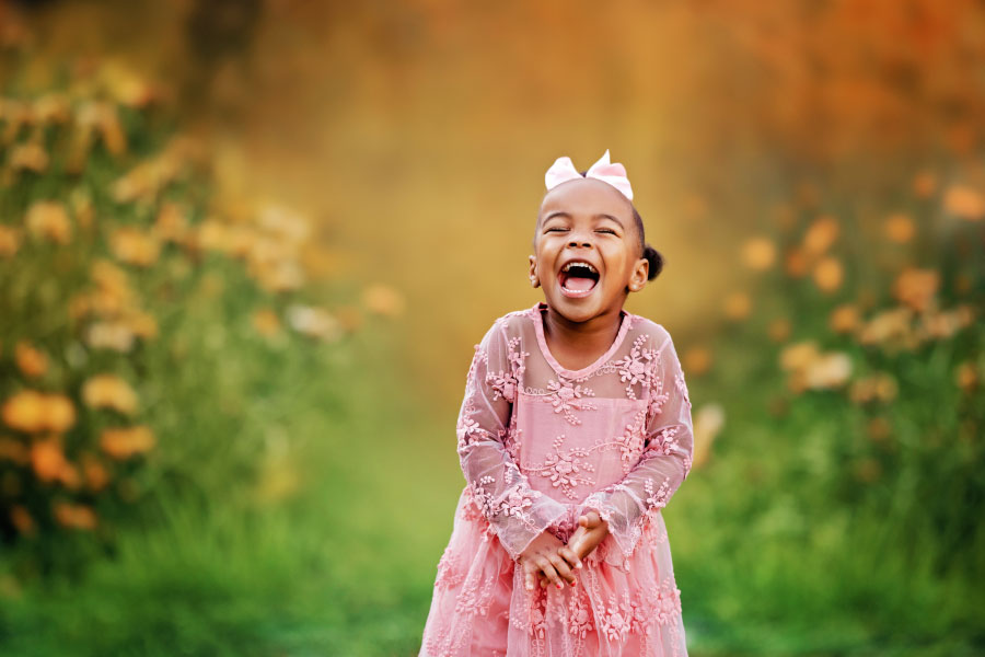 Douglasville kids' photographer, girl laughing by yellow flowers