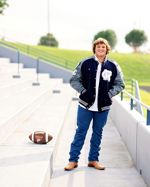 West Georgia senior portrait photographer, football player on bleachers