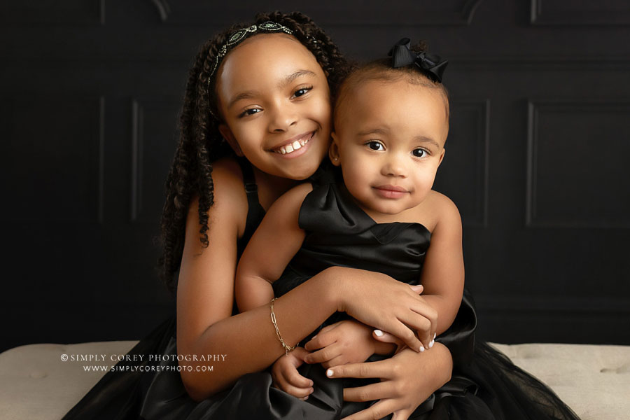 family photographer near Villa Rica, studio portrait of sisters in black dresses