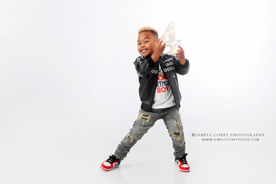 Newnan children's photographer, child holding marquee four on white backdrop